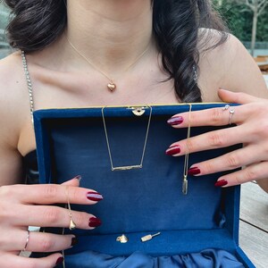 May include: A blue velvet jewelry box with a variety of gold necklaces and earrings. The box is open and the jewelry is displayed on a blue velvet lining.