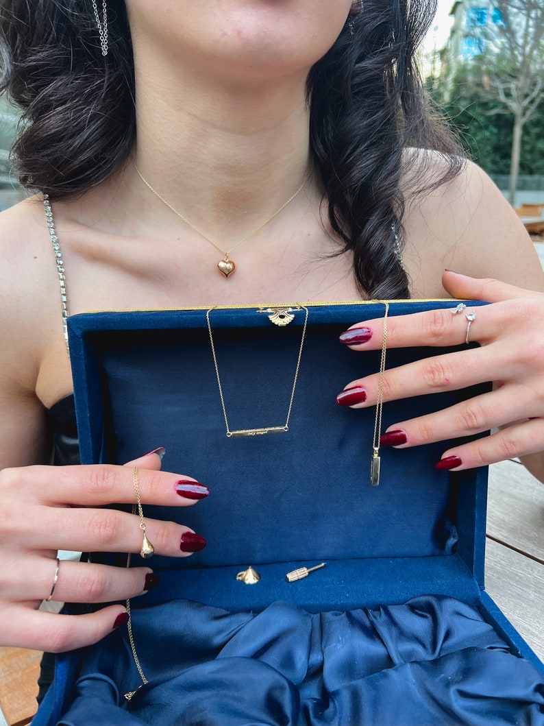 May include: A blue velvet jewelry box with a variety of gold necklaces and earrings. The box is open and the jewelry is displayed on a blue velvet lining.