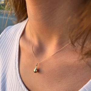 Gold teardrop ashes urn necklace worn on model’s neck, minimalist memorial jewelry