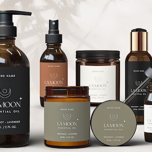 May include: A set of six amber glass bottles with black labels and gold accents. The bottles contain essential oils and candles. The labels feature a crescent moon and star design and the text "LA MOON ESSENTIAL OIL" with the scent "BERGAMOT - LAVENDER" and the volume "60 ML / 2 FL OZ."