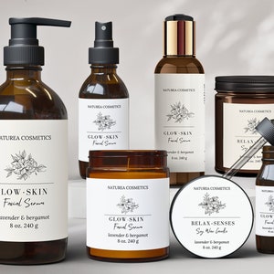 May include: A set of brown glass bottles and jars with white labels featuring a floral design and the text "Naturaea Cosmetics". The products include a facial serum, a soy wax candle, and a body oil. Each product is labelled with "Glow-Skin" and "Relax-Senses" and includes the scent "lavender & bergamot".