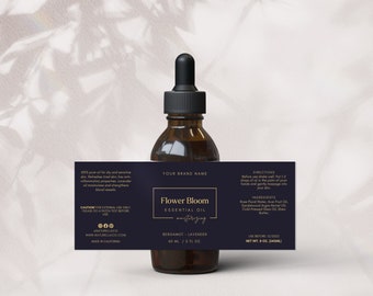 Pode incluir: Um rótulo azul escuro com letras douradas para um frasco de 60 ml de óleo essencial Flower Bloom. O rótulo diz "Flower Bloom Óleo Essencial Hidratante Bergamota - Lavanda 60 ml / 2 fl oz". O frasco é feito na Califórnia.