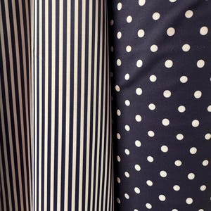 May include: Two fabric swatches, one with white stripes on a navy blue background and the other with white polka dots on a navy blue background.