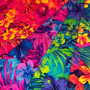 May include: Bright fabric with a tropical floral design. The pattern displays large hibiscus flowers and lush leaves in pink, purple, blue, green, yellow, and orange. The fabric is folded, showing the colourful print.