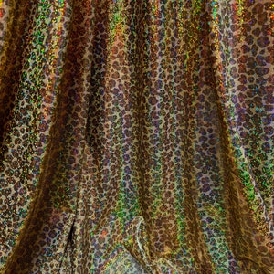 May include: Gold fabric with a leopard print pattern. The fabric has a shimmery, iridescent finish.