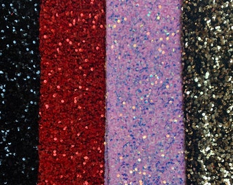 Op de afbeelding: Vier stofstalen met een paillettenstructuur. De stalen zijn zwart, rood, paars en goud.