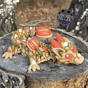 May include: A tan dragon figurine with orange and white details, and a matching orange object, displayed on a weathered wooden surface. The image includes an "AUTHORIZED SELLER" seal.