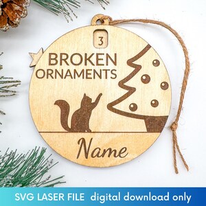 K&ouml;nnte beinhalten: Ein h&ouml;lzerner Weihnachtsbaumschmuck mit einer Katzensilhouette, einem Weihnachtsbaum und dem Text "BROKEN ORNAMENTS". Der Schmuck ist mit "3" nummeriert und hat Platz f&uuml;r einen Namen.