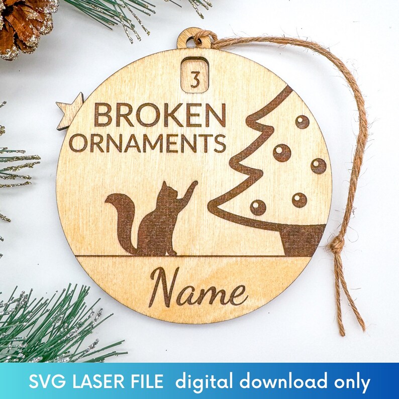 K&ouml;nnte beinhalten: Ein h&ouml;lzerner Weihnachtsbaumschmuck mit einer Katzensilhouette, einem Weihnachtsbaum und dem Text "BROKEN ORNAMENTS". Der Schmuck ist mit "3" nummeriert und hat Platz f&uuml;r einen Namen.