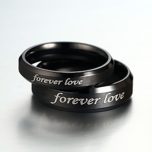 May include: Two black metal rings, each inscribed with the words "forever love".