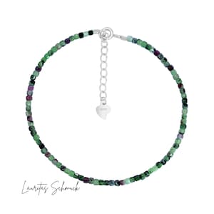 Könnte beinhalten: Ein filigranes Armband mit kleinen, quadratisch geschliffenen Perlen in Grün- und Lilatönen. Es hat eine silberfarbene, verstellbare Kette und einen Verschluss. Der Text "Lauritas Schmuck" befindet sich am unteren Bildrand.