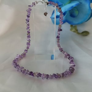 Könnte beinhalten: Eine Halskette aus violetten Amethyst-Chips mit einem silbernen Herz-Anhänger.