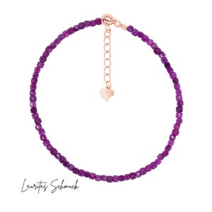 Könnte beinhalten: Ein zartes Fußkettchen mit kleinen, quadratisch geschliffenen, tiefvioletten Edelsteinen. Die verstellbare Kette und der Verschluss sind roségoldfarben. Das Fußkettchen wird auf weißem Hintergrund präsentiert. Der Text "Lauritas Schmuck" steht unten.