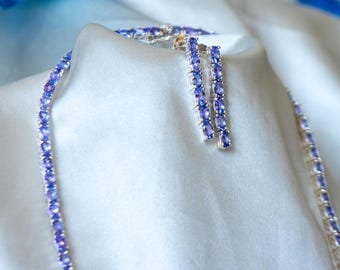 May include: A silver necklace and earrings set with a row of oval-shaped purple gemstones.