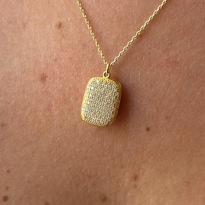 Könnte beinhalten: Eine goldfarbene Halskette mit einem rechteckigen Anhänger. Der Anhänger ist mit vielen kleinen, glitzernden Steinen besetzt. Die Halskette wird um den Hals getragen, mit einer feinen Kette. Der Anhänger ist etwa 2 cm lang.