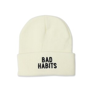 Könnte beinhalten: Eine weiße Strickmütze mit dem in Schwarz gestickten Text "BAD HABITS".
