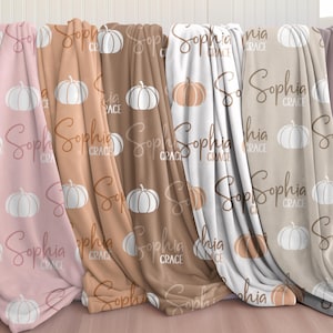 May include: Four plush blankets with a pumpkin and name pattern. The blankets are in shades of pink, brown, beige, and white. The text on the blankets reads "Sophia Grace".