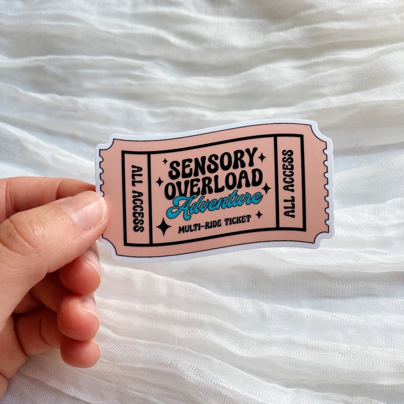 May include: Pink ticket sticker with the text "Sensory Overload Adventure" and "Multi-Ride Ticket" in black and blue lettering. The ticket has "All Access" written on both sides.