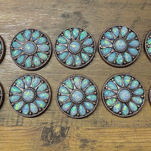 May include: Ten round, copper-toned metal embellishments with a floral design. Each embellishment features a central opal-like stone surrounded by smaller opal-like stones in a flower shape.