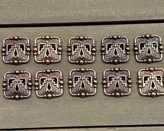 May include: Ten square-shaped metal buttons with a raised design of a stylized eagle with geometric patterns. The buttons are a copper color with black accents.