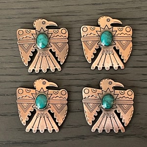 May include: Four silver-toned metal Native American-style eagle charms with turquoise stones. Each charm features a detailed design of an eagle with a sunburst and geometric patterns.