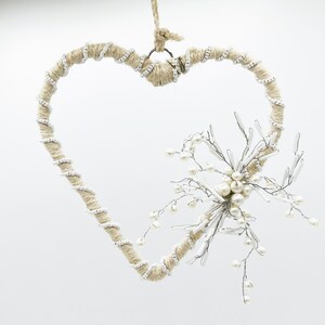 May include: A white and beige heart-shaped wreath with a white pearl and wire flower embellishment.