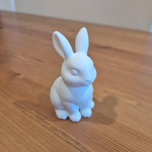 May include: A white ceramic rabbit figurine with long ears and a sitting pose.