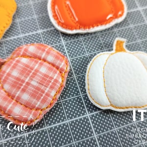 May include: Close-up of several embroidered pumpkin patches in various colors and patterns. One is white with orange stitching, another is orange, and a third is a plaid pattern. The text "So Cute Stitch" and "ITH Machine Embroidery Design" are visible.