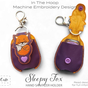 May include: Purple hand sanitizer holder with an orange fox embroidery design. The holder has a snap closure and a silver keychain clip. The text "Sleepy Fox" and "Hand Sanitizer Holder" are also visible.