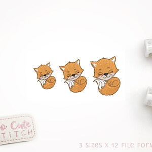 Pode incluir: Três desenhos de raposas bordados em vários tamanhos. As raposas são laranja e têm os olhos fechados. O texto "So Cute Stitch" está sobre um fundo branco.