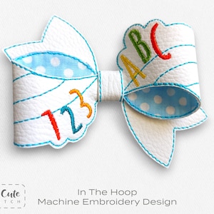 May include: White bow with blue polka dot accents and colorful embroidered numbers and letters. The bow features the numbers "123" and the letters "ABC". The design is a machine embroidery project.