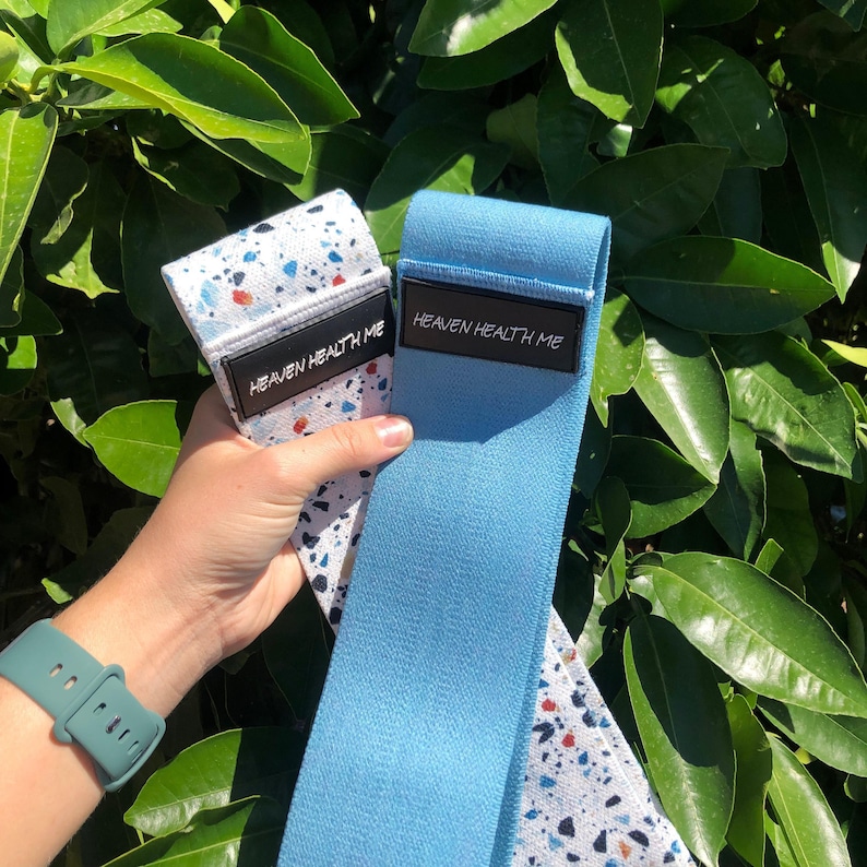 May include: Two exercise resistance bands. One is blue with the text "Heaven Health Me" printed on it. The other is white with black and red speckles and the text "Heaven Health Me" printed on it.
