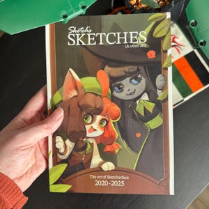 May include: A softcover book titled Sketch's SKETCHES (& other art) featuring a colourful illustration of two anthropomorphic cat characters on the cover. The text reads The art of Sketcherface 2020-2025. The cover art includes green leaves and brown borders.