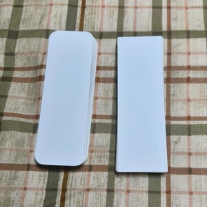 Puede incluir: Un mont&oacute;n de tarjetas rectangulares blancas con esquinas redondeadas, junto a una sola tarjeta. Las tarjetas est&aacute;n en blanco y parecen ser de papel o cartulina. El fondo es un patr&oacute;n de cuadros en tonos marrones y beige.