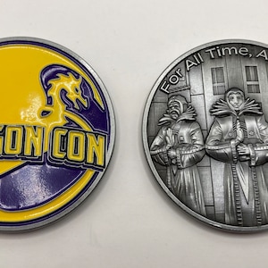 May include: Two-sided Dragon Con commemorative coin. One side features the Dragon Con logo in yellow and purple. The other side has an image of three figures with the text "For All Time, Always".