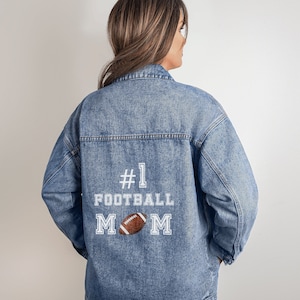 May include: A blue denim jacket with white embroidery that reads "#1 FOOTBALL MOM" with a football graphic.
