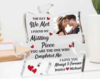 May include: A clear acrylic photo frame shaped like a puzzle piece with the text "The day we met I found my missing piece you are the one who completes me I love you always & forever Jessica Michael". The frame has a small photo of a couple in it.