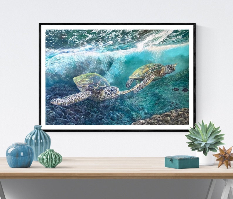May include: Two green sea turtles swim through turquoise water with white foamy waves above them. The turtles are swimming in a coral reef with a dark blue background.