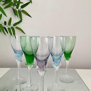 May include: Five clear glass stemmed drinking glasses with twisted stems. The glasses have coloured rims in shades of green, blue, and purple.