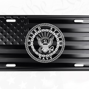 May include: Black license plate featuring a stylized American flag design with the United States Navy emblem. The flag's stars are textured, and the emblem is a white circle with an eagle, anchor, and text.