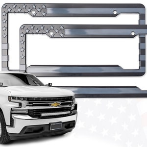 May include: Two silver license plate frames with a faded American flag design. The frames are made of metal and have a black background with a white star pattern.