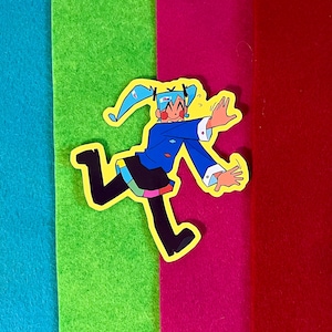 Può includere: Un adesivo colorato con un personaggio in stile anime con capelli blu e una giacca blu, su uno sfondo di feltro giallo, verde acqua, verde, magenta, rosso e blu.