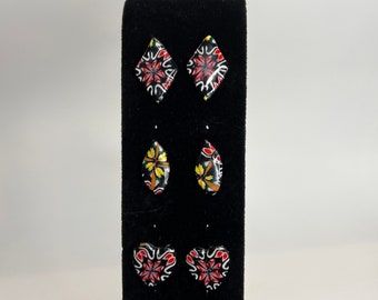 Clay earrings in a kaleidoscope or stained glass pattern. Red black yellow and white in multiple shapes