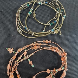 May include: Two sets of layered jewellery, one with copper and green beads and the other with gold and green beads.