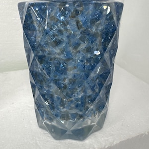 May include: A clear glass bottle with a black pump top. The bottle is filled with blue and white glitter.