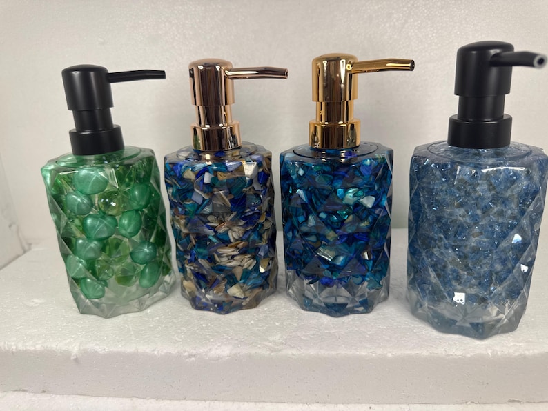 May include: Four decorative soap dispensers with different colored mosaic designs. The dispensers are made of glass and have a gold or black pump.
