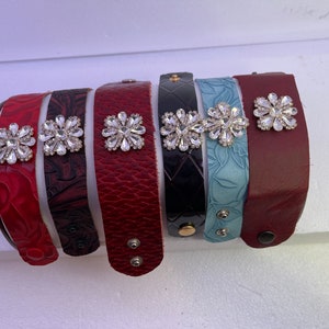 Pu&ograve; includere: Sette braccialetti in pelle con decorazioni in strass. I braccialetti sono di vari colori, tra cui rosso, nero e blu.