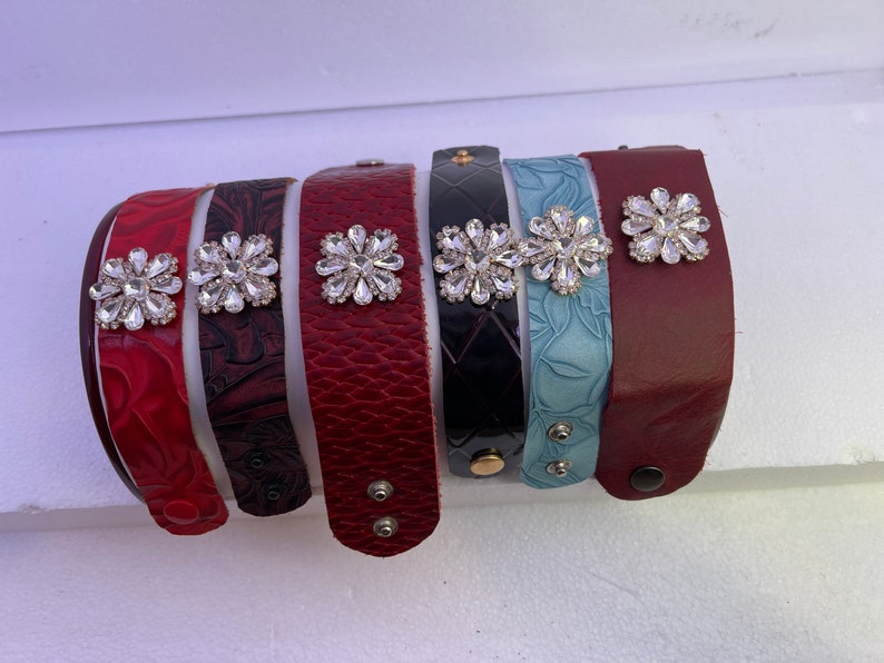 Pu&ograve; includere: Sette braccialetti in pelle con decorazioni in strass. I braccialetti sono di vari colori, tra cui rosso, nero e blu.