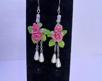 Polymers clay handmade rose earrings. Each petal is individually made so each one is unique. Rose and bud formed on leaf background.