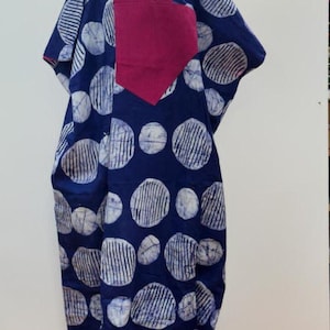 May include: A long, flowing garment with a navy blue background and large white and blue patterned circles. The garment has a magenta-colored neckline and front panel. The sleeves are wide and the fabric appears to be lightweight.